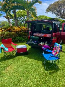 two chairs and a car parked in the grass at Go Camp Maui-Exploring Maui in a Campervan in Ah Fong Village