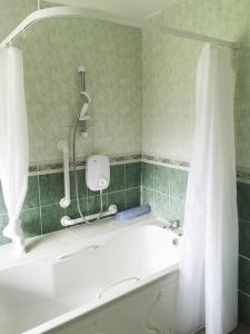 a bathroom with a bath tub with a shower curtain at Woodmount Cottage in Ennistymon