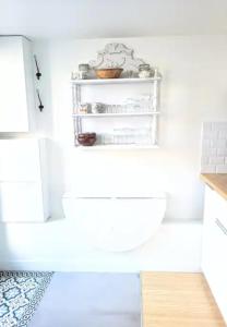a white kitchen with a shelf on the wall at Coup de cœur au jardin piscine - 400m gare Versailles & Paris in Saint-Cyr-lʼÉcole