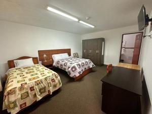 a hotel room with two beds and a dresser at Hotel el sol de los incas in Los Baños del Inca