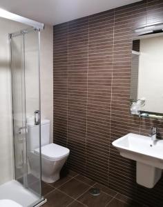 a bathroom with a toilet and a sink and a shower at Apartamentos Rompeolas in Burela de Cabo