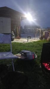 a grill and a chair in the grass with the sun at Charming 1-Bed Cabin in oving in Chichester