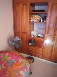 a bedroom with a fan next to a wooden cabinet at Casa de Descanso in Ricaurte