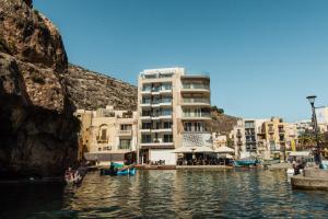 ein Gebäude neben einem Wasserkörper mit Gebäuden in der Unterkunft Blu Waters Boutique Hotel in Xlendi