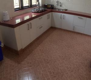 uma cozinha com armários brancos e piso em azulejo em 7TH HEAVEN Kannur em Chakkarakkal