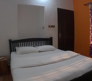 a bedroom with a bed with white sheets and a black door at 7TH HEAVEN Kannur in Chakkarakkal