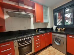 a kitchen with red cabinets and a washing machine at Misterhost Triana Remedios 2BR & parking in Seville