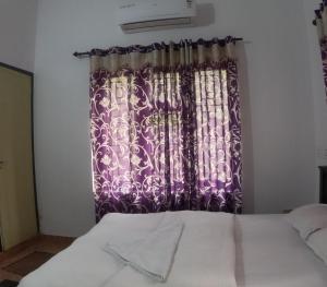 a bedroom with a window with a purple curtain at 7TH HEAVEN Kannur in Chakkarakkal
