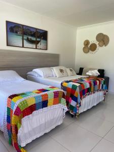 two beds with colorful blankets in a bedroom at Pousada Villa Minduba in Japaratinga