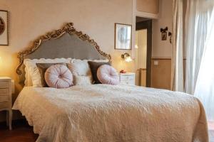 Un dormitorio con una cama grande con almohadas. en LA FINESTRA SUL BORGO Dimora Storica, en Laterina