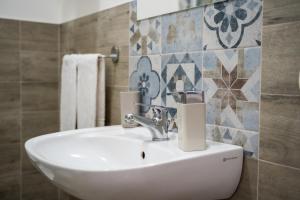 ブゼート・パリッツォーロにあるVilla Pollinaのタイル張りの壁のバスルーム(白い洗面台付)