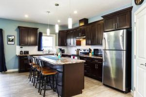 a kitchen with wooden cabinets and a stainless steel refrigerator at Modern Home - King Bed - Garage - Long Stays in Edmonton