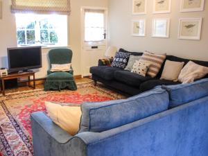 uma sala de estar com um sofá azul e uma televisão em 11 Robinsons Row em Salcombe