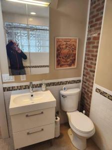 a person taking a picture of a bathroom with a toilet and sink at The Lincoln House in Salem