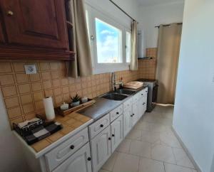 a kitchen with a sink and a window at Enjoy sunset from a wonderful traditional studio-Melina in Ioulis