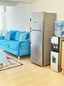 a living room with a blue couch and a refrigerator at Sea la Blue in Ukunda