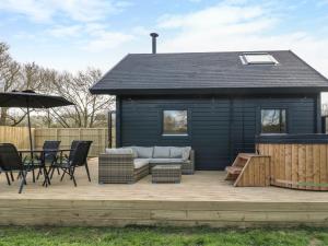 a black shed with a couch and chairs on a deck at Squirrel's Nest in Oakham