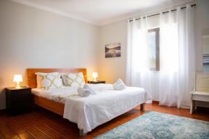 um quarto com uma cama com lençóis brancos e 2 candeeiros em 4Ever Palace - Design & Nature em Alcácer do Sal