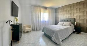 1 dormitorio con 1 cama, TV y silla en Hostal Restaurante Cerqueiro en Laracha