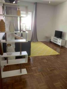 - un salon avec des étagères blanches et un tapis jaune dans l'établissement Carcavelos Maristas BEACH pax5, à Carcavelos