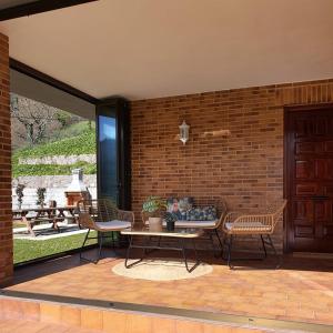 eine Terrasse mit Tisch und Stühlen und einer Backsteinmauer in der Unterkunft MIRADOR PIE DE LA SIERRA in Llanes