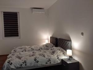 una camera da letto con un letto con un piumone bianco e nero di Apartmani Ćosić - Kuršumlijska banja a Kursumlijska Banja