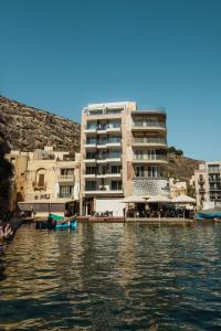 a building next to a body of water with buildings at Blu Waters Boutique Hotel in Xlendi