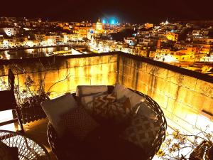 a chair on a balcony with a view of a city at night at Casa Cara in Birgu