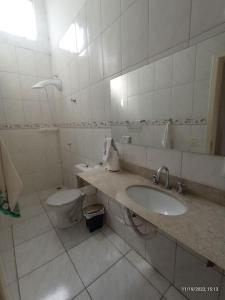Baño blanco con lavabo y aseo en Apartamento 2 Km da BR101 en São José