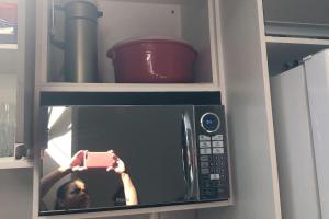 una persona que toma una foto de un microondas en Apartamento 2 Km da BR101 en São José