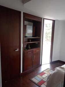 a bedroom with a large wooden cabinet with a television at Habitación central con balcón, baño privado y parqueadero in Duitama
