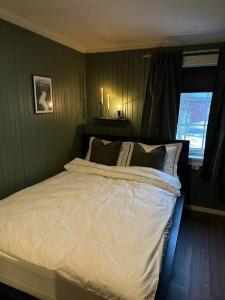 Schlafzimmer mit einem Bett mit weißer Bettwäsche und einem Fenster in der Unterkunft Koselig hytte, nær Finnskogen og Vålerbanen in Åsnes