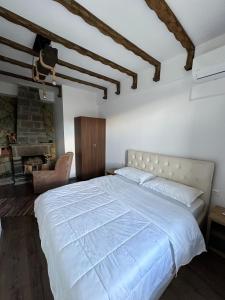a bedroom with a large white bed and a fireplace at GuestHouse "Shtëpia ime" in Përmet