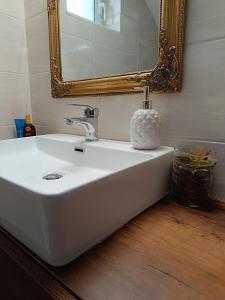 een badkamer met een witte wastafel en een spiegel bij Forever Blue in Salamis