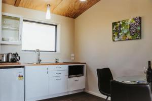 a kitchen with white cabinets and a table and a window at Chalets at Okurukuru in New Plymouth