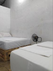 San Vicente de ChucuríにあるDe La Mora Hostal.の白い壁のドミトリールーム ベッド3台