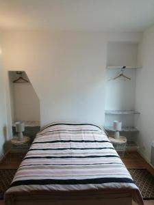ein Schlafzimmer mit einem Bett mit einer gestreiften Decke in der Unterkunft Maison Natis in Tillé