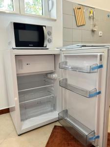 La cuisine est équipée d'un réfrigérateur ouvert et d'un four micro-ondes. dans l'établissement Kuća Antibarium, à Sutomore