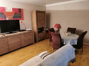 ein Wohnzimmer mit einem TV, einem Tisch und Stühlen in der Unterkunft Appartement entier in Cachan