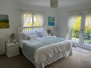 a bedroom with a white bed with white sheets and windows at Lissett Lodge in Battle