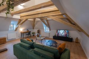 a living room with a green couch and a table at Le 1552 - Gîte de charme - Parking Gratuit in Bergheim