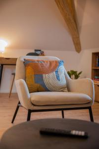 a chair with a pillow on it in a living room at Le 1552 - Gîte de charme - Parking Gratuit in Bergheim