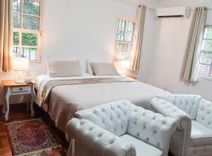 a bedroom with a bed and a couch and windows at Agellum Bed & Breakfast in Domingos Martins