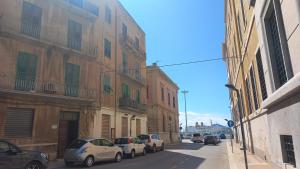 uma fila de carros estacionados numa rua ao lado de edifícios em La Casa di Aurora em Trapani