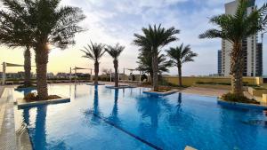 a large swimming pool with palm trees and a building at Beachfront SeaView Home in Lusail