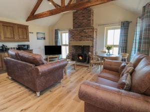 a living room with leather furniture and a fireplace at Glebe Cottage in Alnwick