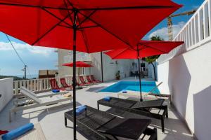 a patio with red umbrellas and a swimming pool at Apartments BINGO in Cavtat