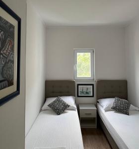 two beds in a small room with a window at Apartments BINGO in Cavtat