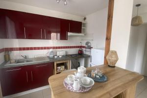 eine Küche mit roten Schränken und einem Holztisch in der Unterkunft Charming house close to the beach in Ouistreham