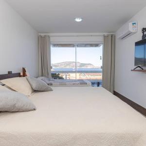 1 Schlafzimmer mit 2 Betten und einem großen Fenster in der Unterkunft CAMBOINHAS BnB in Niterói